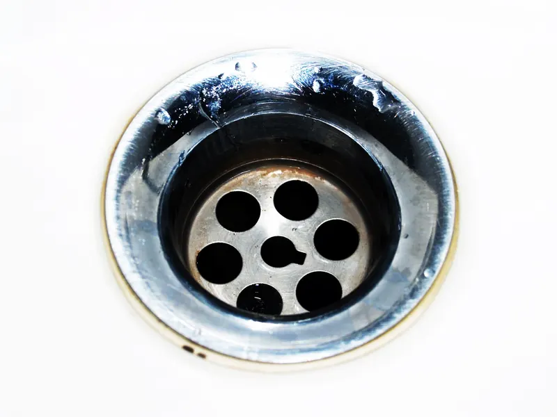 Close-up of a chrome sink drain with water droplets