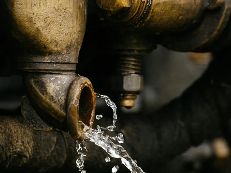 Water spraying from a corroded brass valve on an old pipe